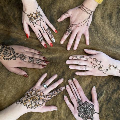 Picture of six hands with different henna tattoo designs