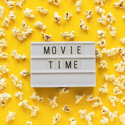 Movie Time on a Board on a Yellow Background surrounded by popped popcorn